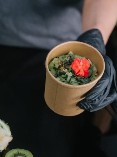 A hand holding a salad bowl with fresh vegetables and a colorful garnish, emphasizing healthy eating.