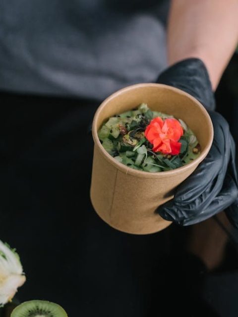 A hand holding a salad bowl with fresh vegetables and a colorful garnish, emphasizing healthy eating.