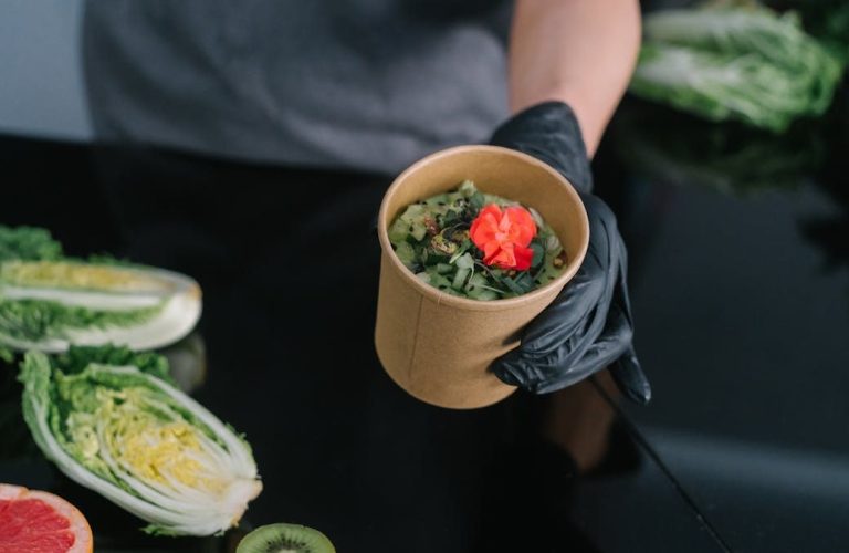 A hand holding a salad bowl with fresh vegetables and a colorful garnish, emphasizing healthy eating.
